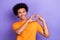 Closeup portrait optimistic young guy wear orange trendy t shirt demonstrate his love symbol fingers isolated on purple
