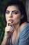 Closeup portrait of pensive thoughtful beautiful young Caucasian woman with black hair, blue eyes, looking in camera