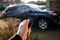 A closeup portrait of a person holding a car key in his hand pressing the unlock button. The keyless remote control has unlock and