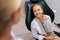 Closeup portrait of positive cute little girl having conversation with unrecognizable dentist, learning about healthy