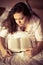 Closeup portrait of reading interesting book relaxing charming sweet brunette girl in white shirt laying on bed