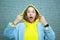 Closeup portrait of shocked girl with brown eyes and open mouse look at the camera holding yellow hood by both hand. Concept of
