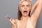 Closeup portrait of shocked scared frighten woman shaving armpit with pink shaver isolated on gray background, raised arm,