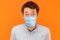 Closeup portrait of shocked young worker man with surgical medical mask standing and looking at camera with big eyes