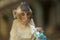 Closeup portrait of small monkey with big thoughtful eyes. Monkey chewing gum in plastic bag. Ecology garbage problem