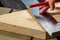 A closeup portrait of someone using a stainless steel L-square or snag to measure and draw a perfectly perpendicular line on a