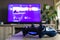 A closeup portrait of a sony playstation 4 controller in front of a television with the playstation home menu displayed on it. The