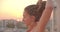 Closeup portrait of spiritual female with dreadlocks doing yoga on rooftop with beautiful city landscape sunset on