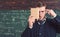 Closeup portrait of student holding book in front of his face and pressing finger over forehead. Thoughtful intelligent