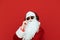 Closeup portrait of stylish Santa Claus wearing sunglasses and headphones, isolated on red looks into the camera and corrects his