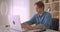 Closeup portrait of successful attractive caucasian businessman using laptop looking at camera in office indoors