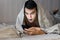 Closeup portrait of surprised young man messaging on smart phone in bed at home in the morning . the concept-social networking, te