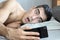 Closeup portrait of surprised young man messaging on smart phone in bed at home in the morning . the concept-social networking, te