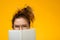 Closeup portrait of teenager hiding behind notebook