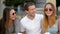 Closeup Portrait of Three Smiling Friends Sitting with Cups of Coffee Outdoors and Talking During Summer Time. Two Girls