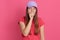 Closeup portrait of tired yawning woman covering her mouth with fist, looks exhausted, wearing t shirt and baseball cap, wants