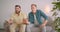 Closeup portrait of two caucasian male friends watching sports on TV and celebrating together sitting on couch at home