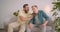 Closeup portrait of two caucasian men watching football on TV emotionally together sitting on couch at home indoors