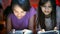 Closeup portrait of two teenage girls typing messages on smartphones in bed at night