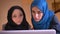 Closeup portrait of two young muslim businesswomen in hijabs discussing the data in front of the laptop. Boss