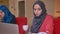 Closeup portrait of two young successful arabian female office workers in hijabs typing on the laptops on the workplace