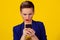 Closeup portrait upset skeptical unhappy serious woman looking at texting on phone displeased with conversation isolated on yellow