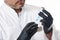 Closeup portrait on a white background of a handsome male doctor, plastic surgeon wearing black gloves and holding a syringe with