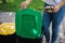 Closeup portrait woman hand throwing crumpled paper bag in recycling bin. Outdoors recycling bins different colours