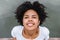 Closeup portrait of young afro woman smiling and blink with eye with happy face expression, enjoying warm summer wind while