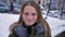 Closeup portrait of young attractive brunette caucasain female cheerfully smiling and looking at camera in a winter day