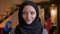 Closeup portrait of young beautiful arabian businesswoman in black hijab looking at camera and laughing happily on the