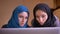 Closeup portrait of young beautiful muslim businesswomen discussing a work topic using the laptop indoors on the