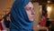 Closeup portrait of young beautiful muslim female in blue hijab turning from the side and looking straight at camera