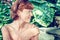 Closeup portrait of young beautiful woman on green leafs back. Tropical lady scene. Bali island.