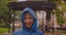 Closeup portrait of young caucasian female in blue raincoat looking at camera smiling happily while it is raining