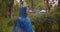 Closeup portrait of young caucasian female in blue raincoat walking in park while it is raining outdoors