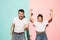 Closeup portrait of young couple, man, woman. One being excited happy smiling, other serious, concerned, unhappy on pink