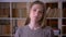 Closeup portrait of young cute attractive female student looking at camera smiling with shyness in the college library