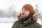 Closeup portrait of young man in khaki winter jacket and brown hat