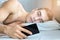 Closeup portrait of a young man, looks at messages on a smartphone in bed at home in the morning. the concept-social networking, t