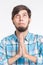 Closeup portrait young man praying, imploring, hands clasped hoping for best asking forgiveness, miracle isolated white