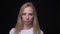 Closeup portrait of young pretty blonde female being sad and angry looking at camera with background isolated on black