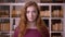 Closeup portrait of young redhead attractive caucasian female student looking at camera in the college library