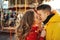 Closeup portrait young romantic enamored couple hugging and kissing on french carousel background.