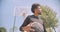 Closeup portrait of young strong African American male basketball player throwing a ball into a hoop outdoors on the