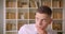 Closeup portrait of young successful attractive businessman looking at camera in library indoors with bookshelves on