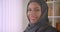 Closeup portrait of young successful muslim businesswoman in hijab looking at camera smiling cheerfully in office
