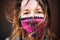 Closeup portrait of a young woman wearing a plaid handmade face mask with disheveled hair waving in the wind.