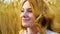 Closeup portrait of young woman with wheat ear day dreaming in wheat field