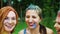 Closeup portraits of young women in Holi paints talk and smile in green park